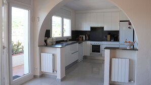 Een moderne keuken met witte kasten, een inbouwoven en een raam dat voor natuurlijk licht zorgt.