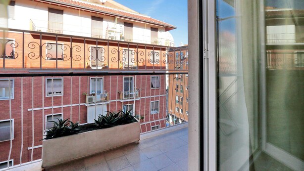 A balcony with a view of a building with a tiled roof and a brick facade. There are potted plants on the balcony. - Marvelous apartment center of Rome 100 metres from St. Peter's Square Free Wifi  (Roma)