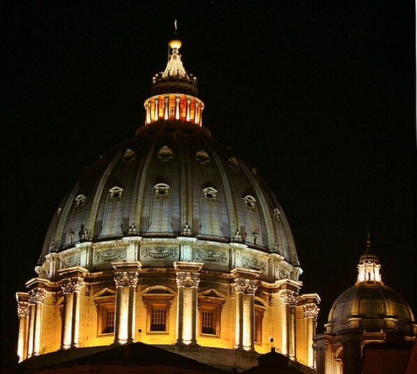 A large, illuminated dome structure with classical architectural features, including columns and decorative elements.