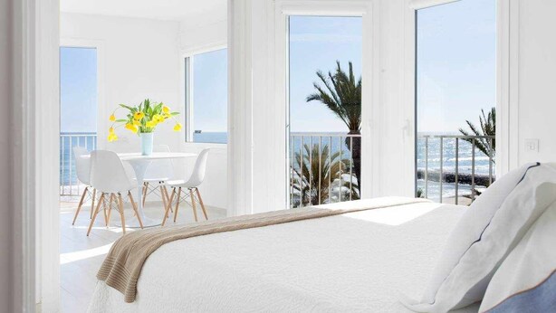A bedroom with a large bed, a balcony with a table and chairs, and a view of the sea. - Sitges Bellavista Spectacular Sea Views (Sitges)