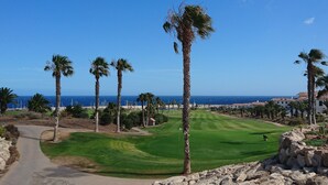 Un parcours de golf offrant une vue dégagée sur l’océan et bordé d’un chemin pavé.
