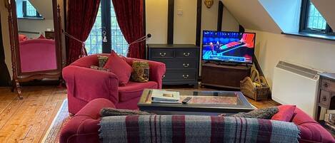 A cozy living room with a red sofa, a television, and a patterned rug.