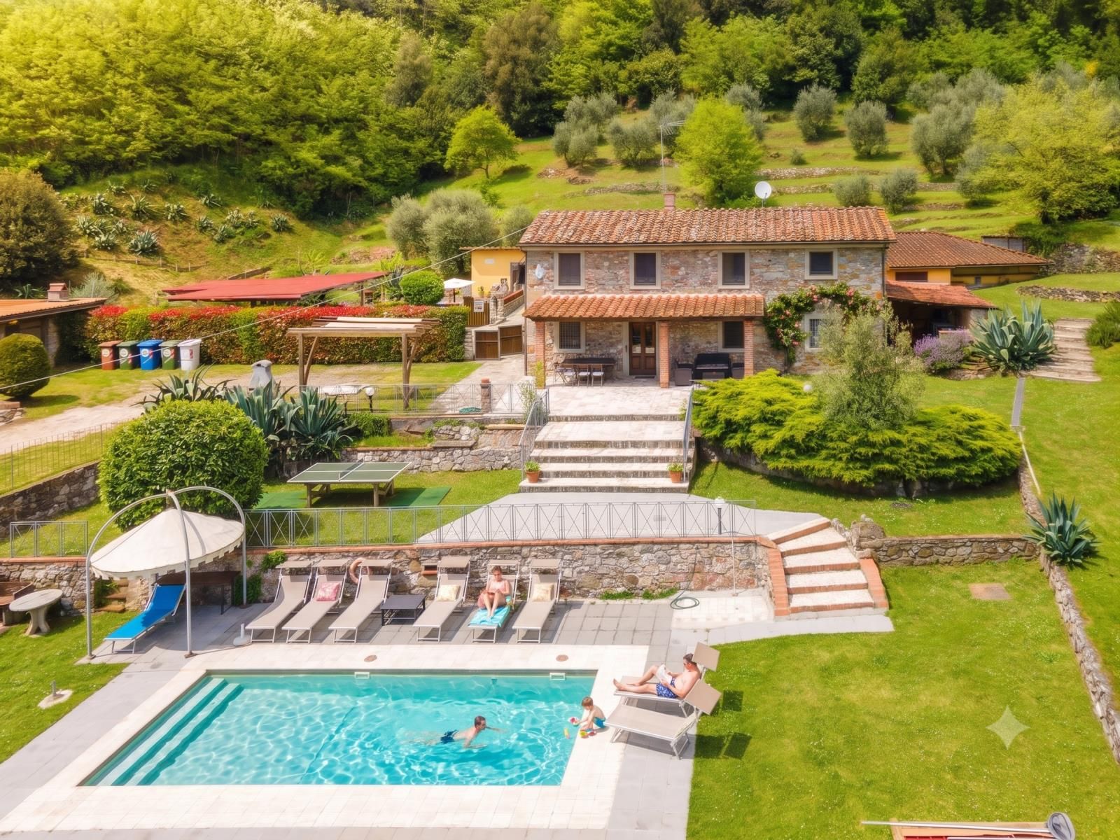 A villa with a swimming pool, outdoor seating, and a garden.