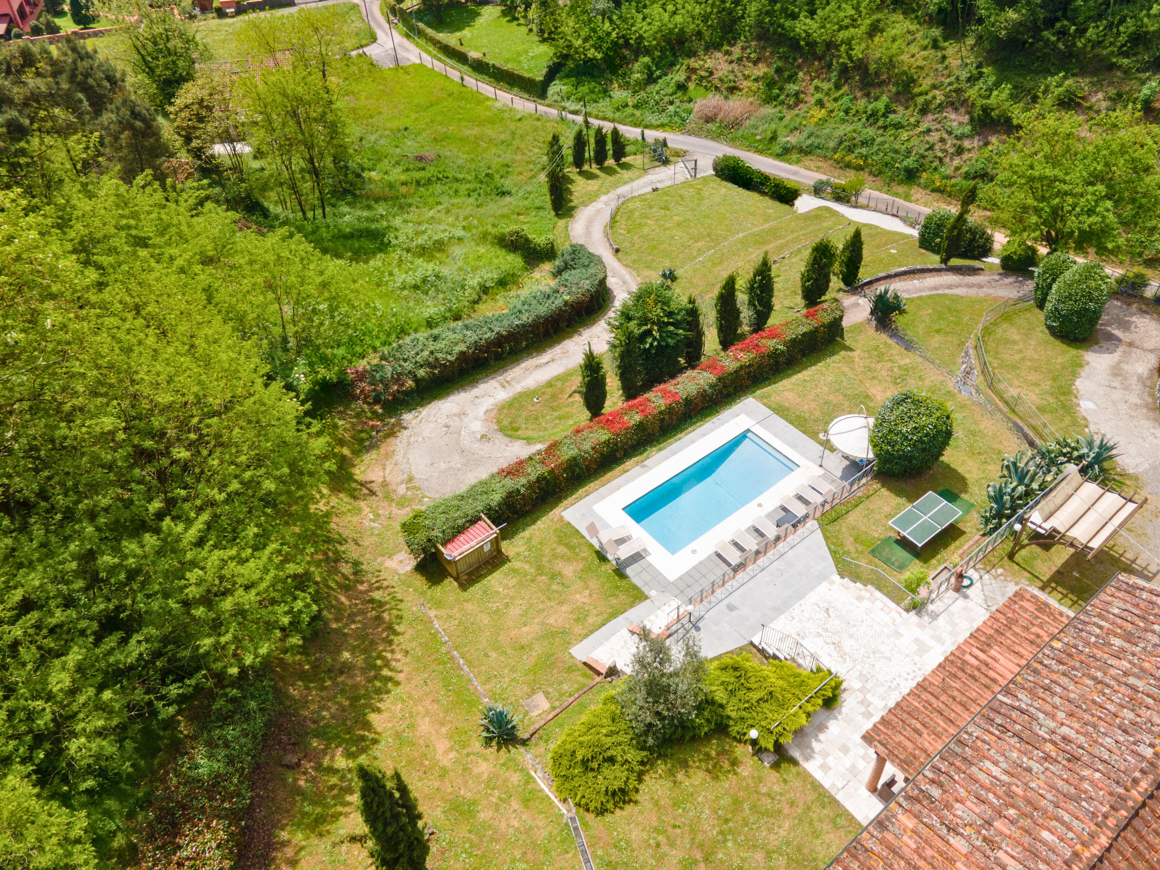Vue aérienne d’une propriété dotée d’une piscine, d’un court de tennis et d’un jardin bien entretenu.
