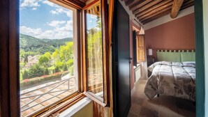 Ein Schlafzimmer mit einem Bett, einem Fenster mit Blick auf eine grüne Landschaft und einer Holzbalkendecke.