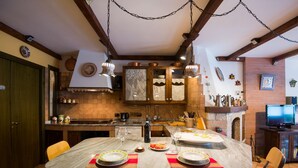 Une cuisine avec des meubles de rangement en bois, un îlot central et un coin repas avec des chaises.
