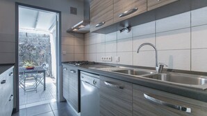 Una cocina moderna con lavavajillas, doble pileta y vista al patio exterior.
