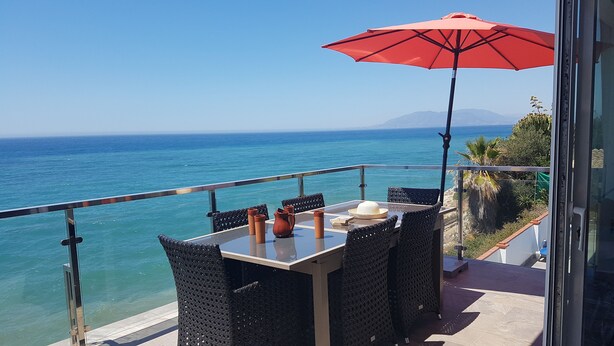 A balcony with a table, chairs, and a red umbrella overlooking the sea. - House on the Mediterranean, swimming pool, BBQ Garden, WiFi, air conditioning (Rincon de la Victoria)