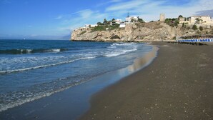 A coastal beach with a rocky cliff, a few buildings, and a clear blue sky. - House on the Mediterranean, swimming pool, BBQ Garden, WiFi, air conditioning (Rincon de la Victoria)