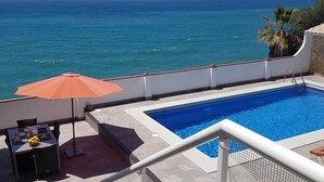 A swimming pool with a view of the ocean, a table with chairs, and an umbrella. - House on the Mediterranean, swimming pool, BBQ Garden, WiFi, air conditioning (Rincon de la Victoria)