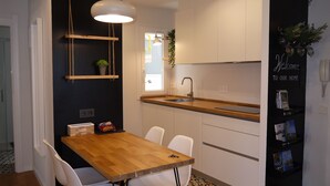 A modern kitchen with white cabinets, a wooden countertop, and a hanging pendant light. - Apartment overlooking the cathedral, terrace, wifi, parking included (Donostia)