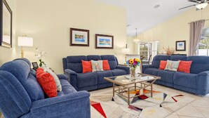 A living room with blue sofas, a coffee table, and framed pictures on the walls.