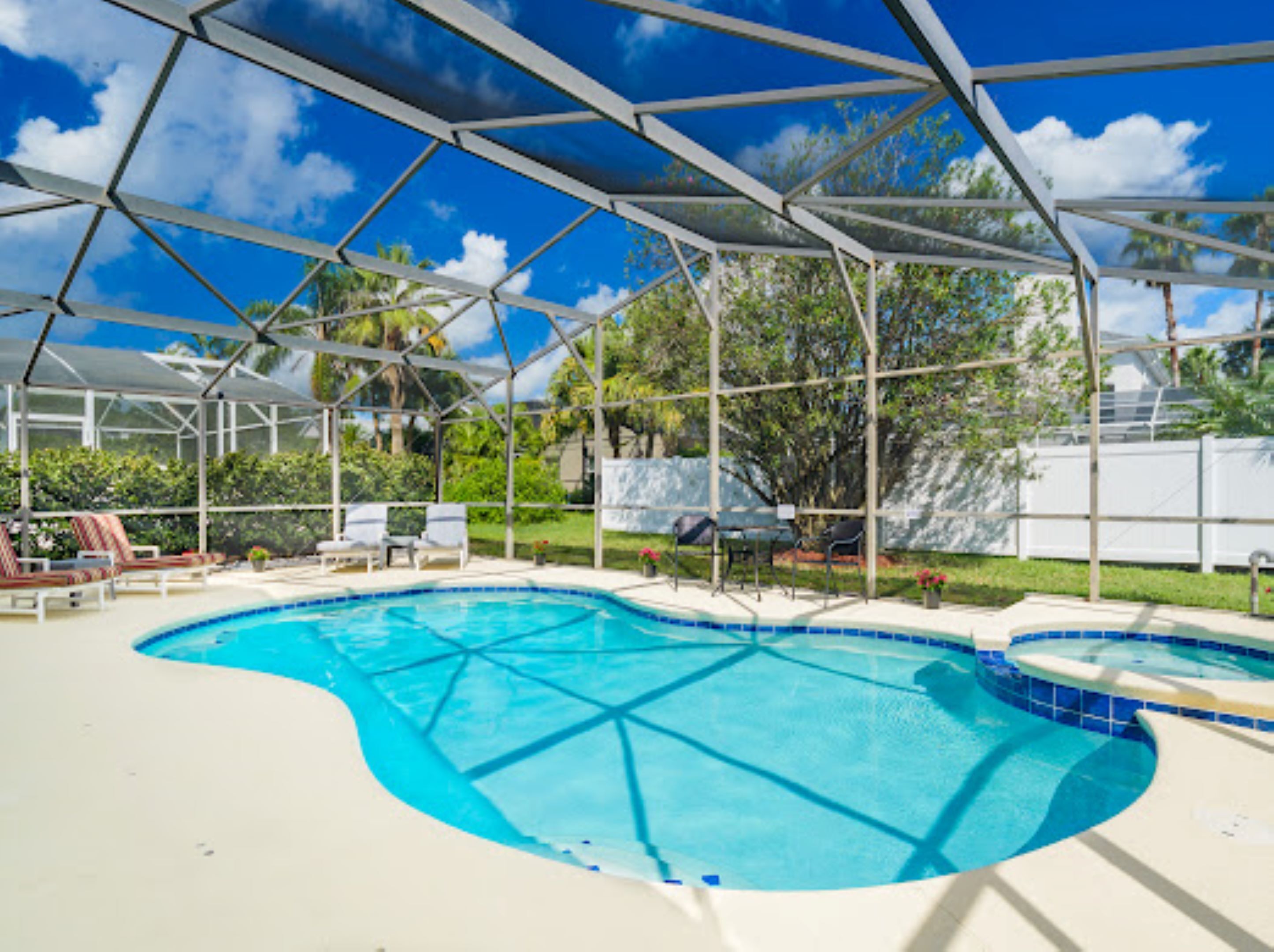 A swimming pool with a glass enclosure, surrounded by lounge chairs and a covered patio area.