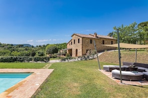 A stone house with a swimming pool and outdoor seating.