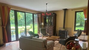 A living room with a sofa, chairs, a table, a fireplace, and a view of the outdoors.
