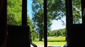 A room with two chairs facing a large window overlooking a green landscape.