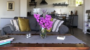 A living room with a sofa, a coffee table with a vase of flowers, and a bookshelf. - CHARMING VILLA 💖Panoramic views of sea & mountain, private sunny terraces, pool (Saint-Paul-De-Vence)