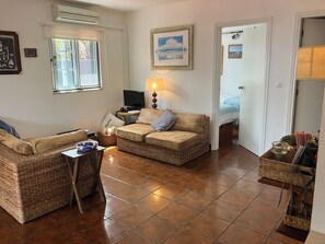 Una sala de estar con un sofá, una televisión, una lámpara y un cuadro en la pared.
