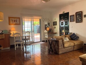 Una sala de estar con sofá, sillas, una mesa de comedor y una zona de cocina con mostrador y armarios.