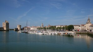 Un port esportiu amb nombroses embarcacions amarrades, edificis històrics i una torre destacada al fons.