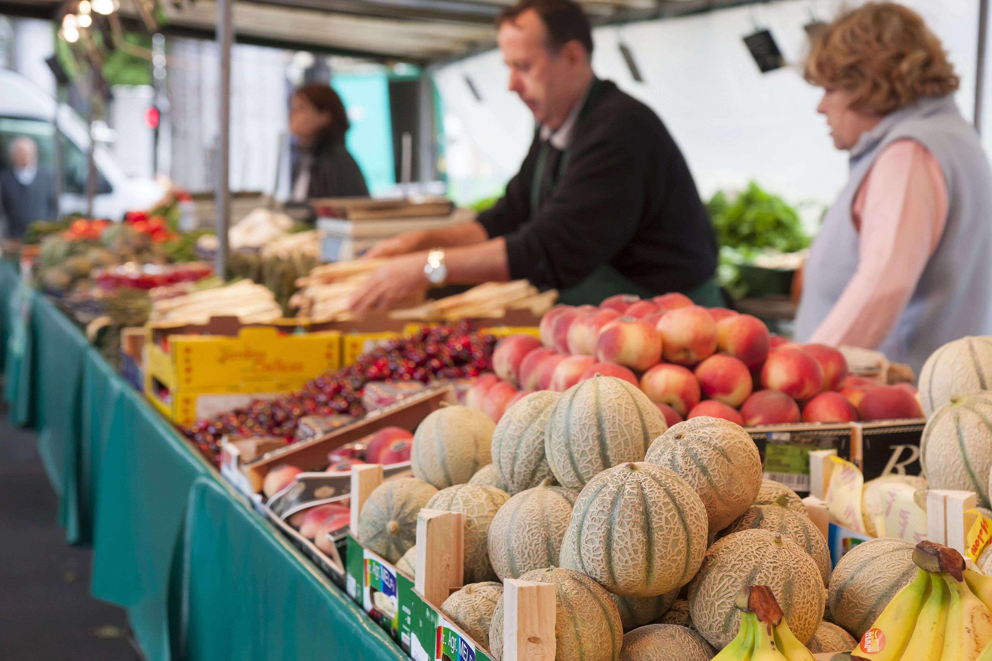 Ein Marktstand mit verschiedenen Früchten und Gemüsesorten, darunter Melonen und Äpfel.