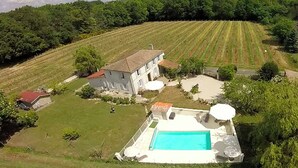 Una casa gran amb piscina, envoltada per un jardí ben cuidat i un viñedo.
