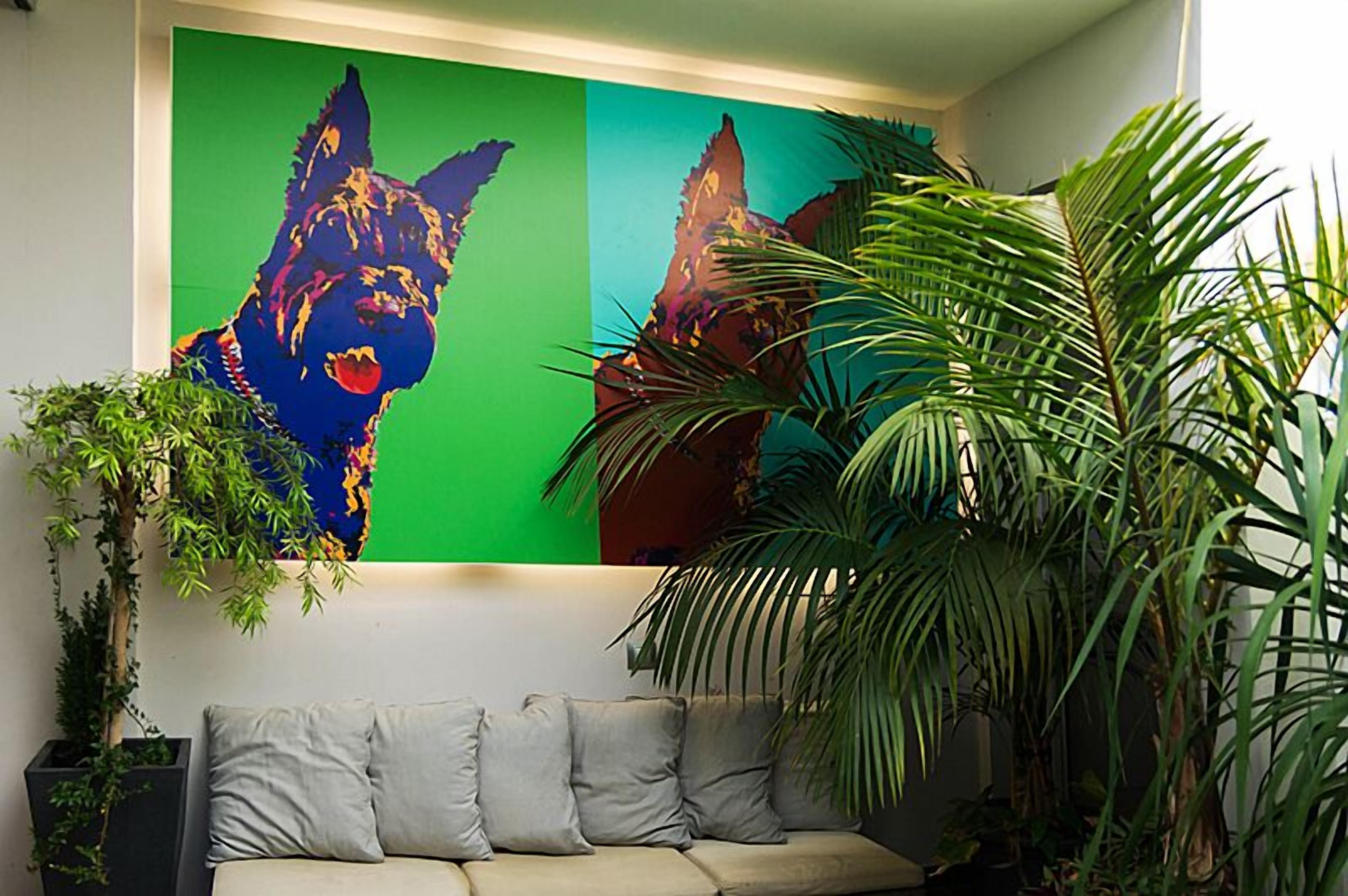 Ein Zimmer mit grüner Wand, einem beigen Sofa und einem großen Gemälde eines Hundes.