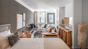 Una habitación de hotel moderna con una cama grande, un escritorio, un sofá y un comedor.