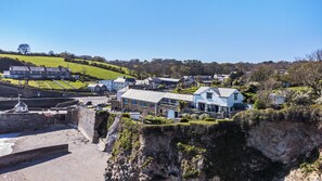 A coastal village with stone buildings, a harbor, and a cliff overlooking the sea.