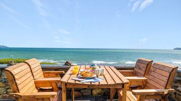 A wooden table and chairs with a view of the ocean.