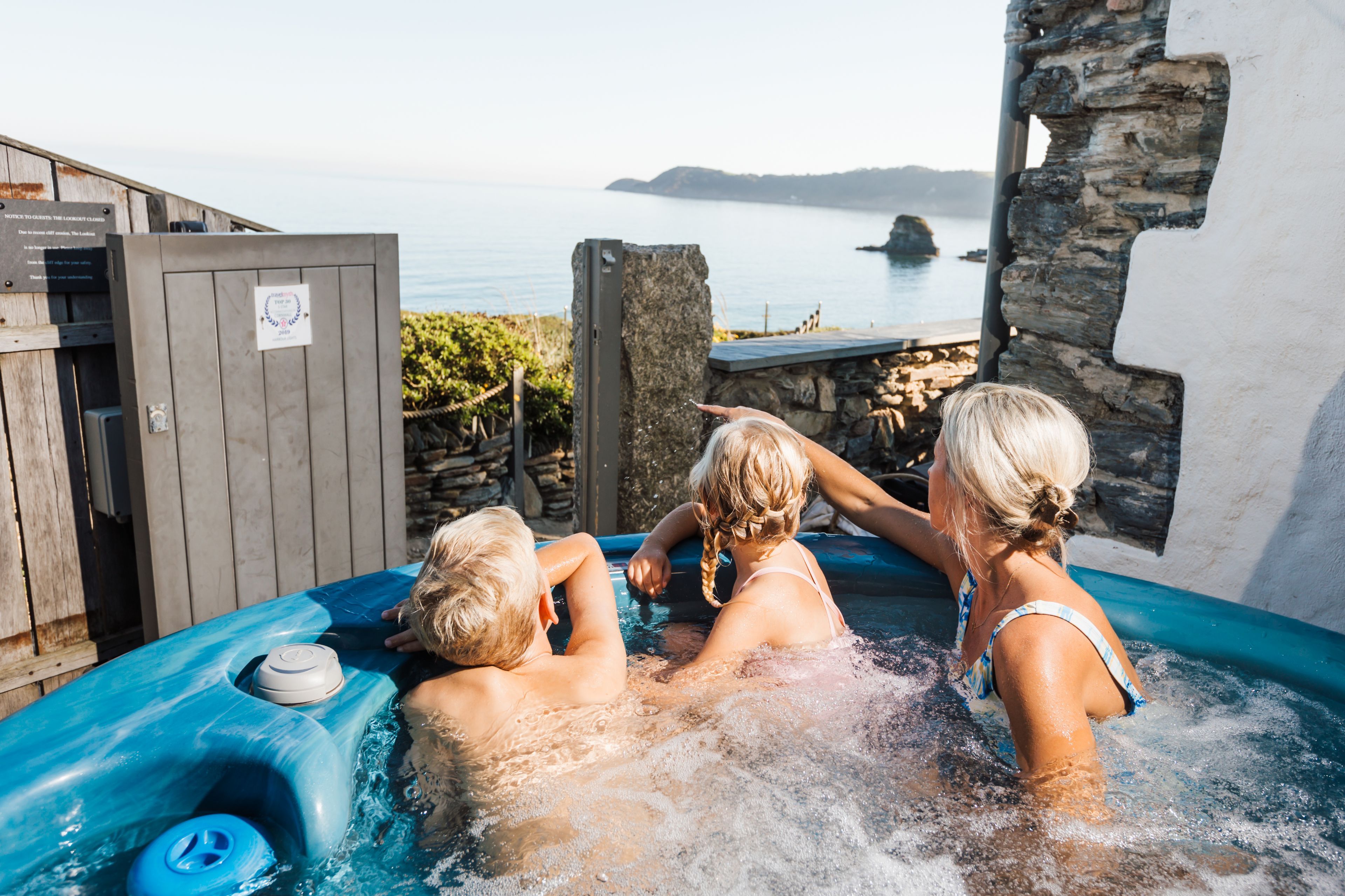 A hot tub with a view of the sea and a stone wall.