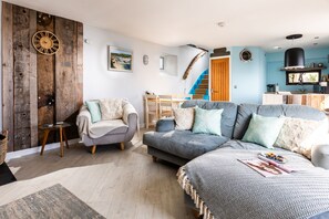 Una sala de estar moderna con un sofá gris, una silla de madera y un comedor con mesa y sillas.