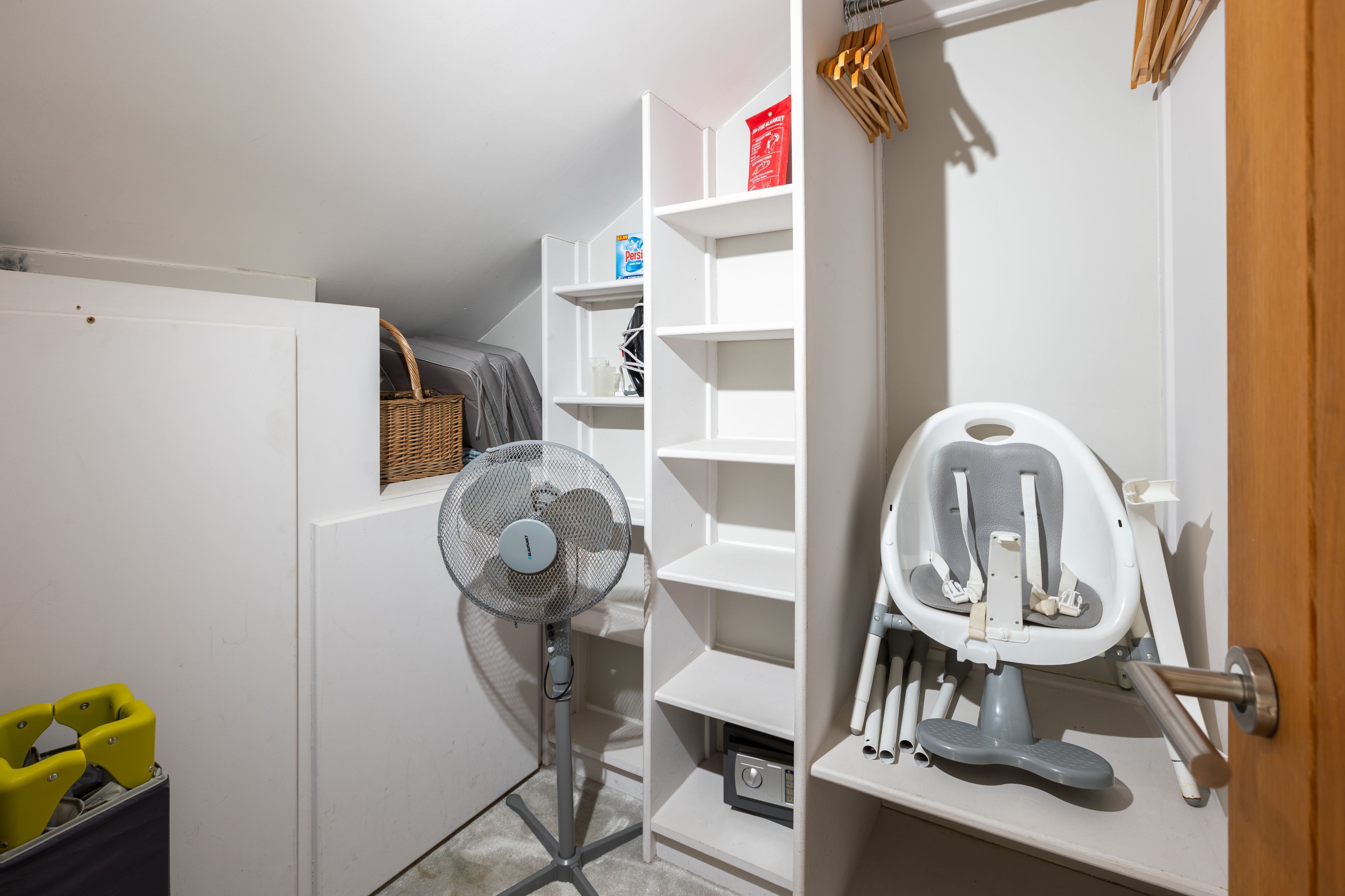 Et opbevaringsskab med hylder, en ventilator og en gåvogn.
