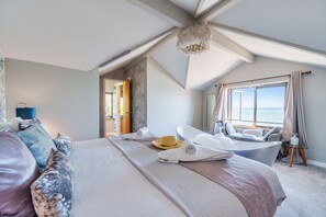 A bedroom with a large bed, a bathtub, and a view of the sea. - As seen on TV! Luxurious Beach Front Cottage with Hot Tub, Log Burner & Sea Views (Charlestown)