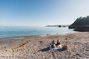 A pebble beach with a picnic setup. - As seen on TV! Luxurious Beach Front Cottage with Hot Tub, Log Burner & Sea Views (Charlestown)