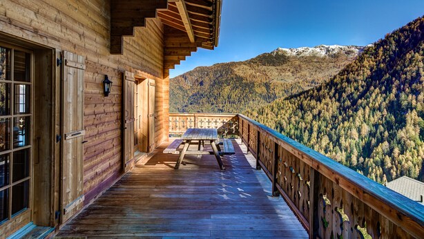 Une cabane en bois dotée d’un balcon donnant sur une montagne boisée.