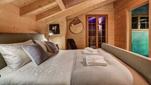 Une chambre à coucher dans une cabane en bois, avec un lit, des oreillers, un miroir et une vue sur une pièce aux carreaux bleus.