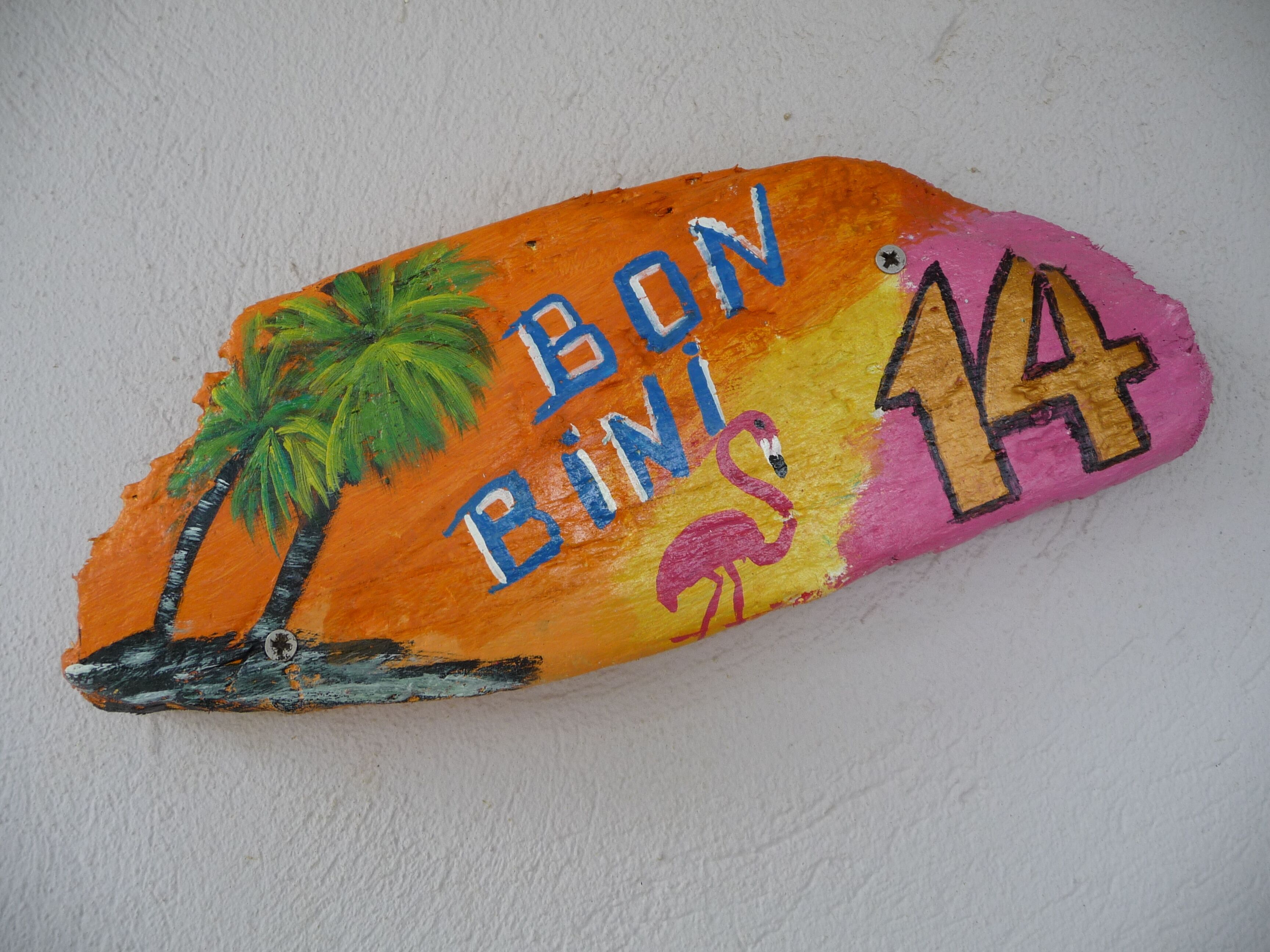 A painted wooden sign with palm trees, a flamingo, and the text "BON BINI 14".