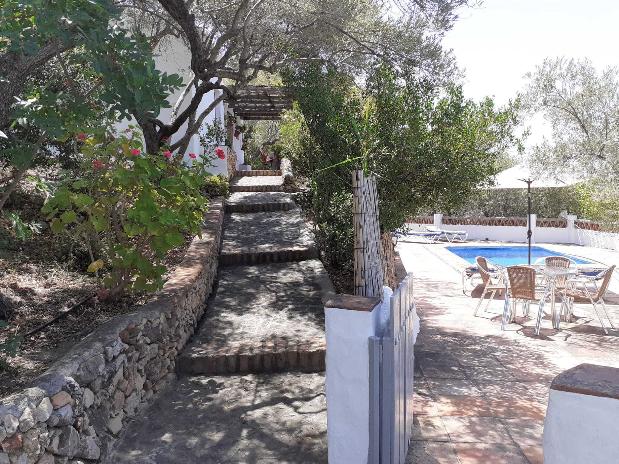 Eine Steintreppe führt zu einem Poolbereich mit Gartenmöbeln.