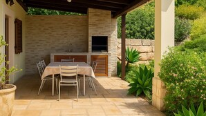 An outdoor patio with a stone table and chairs, a grill, and a stone wall backdrop. - wonderful villa with beautiful view of the mountains  (Estoi)