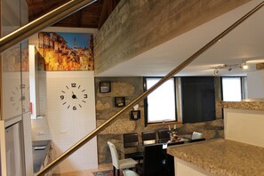 Une cuisine moderne avec un mur en pierre, une grande horloge et un coin repas comprenant une table et des chaises.