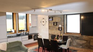 Ett kompakt bostadsutrymme med ett litet kök, en matplats och en mysig sittgrupp.
