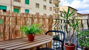 Un balcón con una mesa de madera, una planta en maceta y una silla.