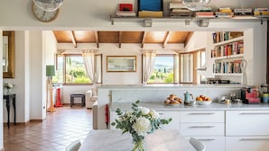 A modern kitchen with a marble countertop, a coffee machine, and a view of the countryside.