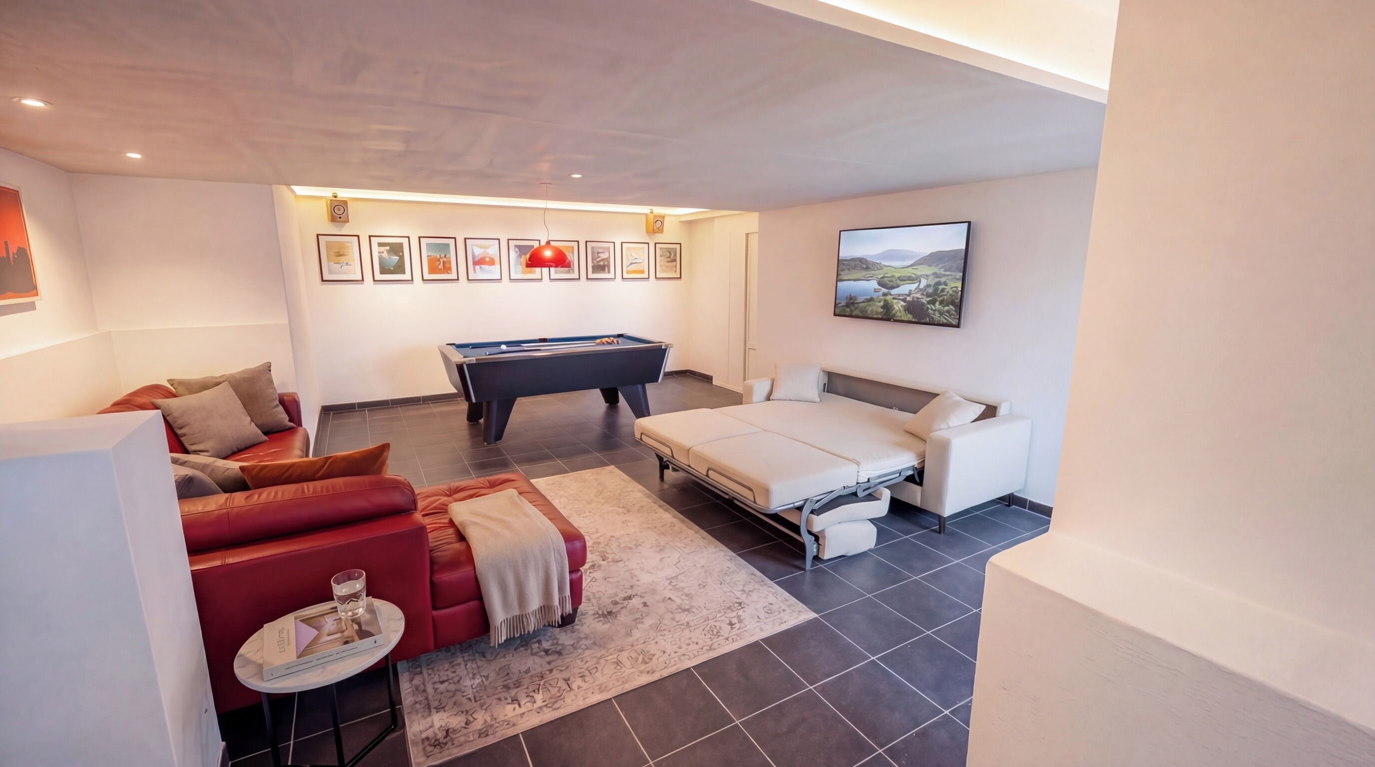 Ein modernes Schlafzimmer mit Billardtisch, einer Couch, einem Bett und einem kleinen Tisch mit einem Glas.