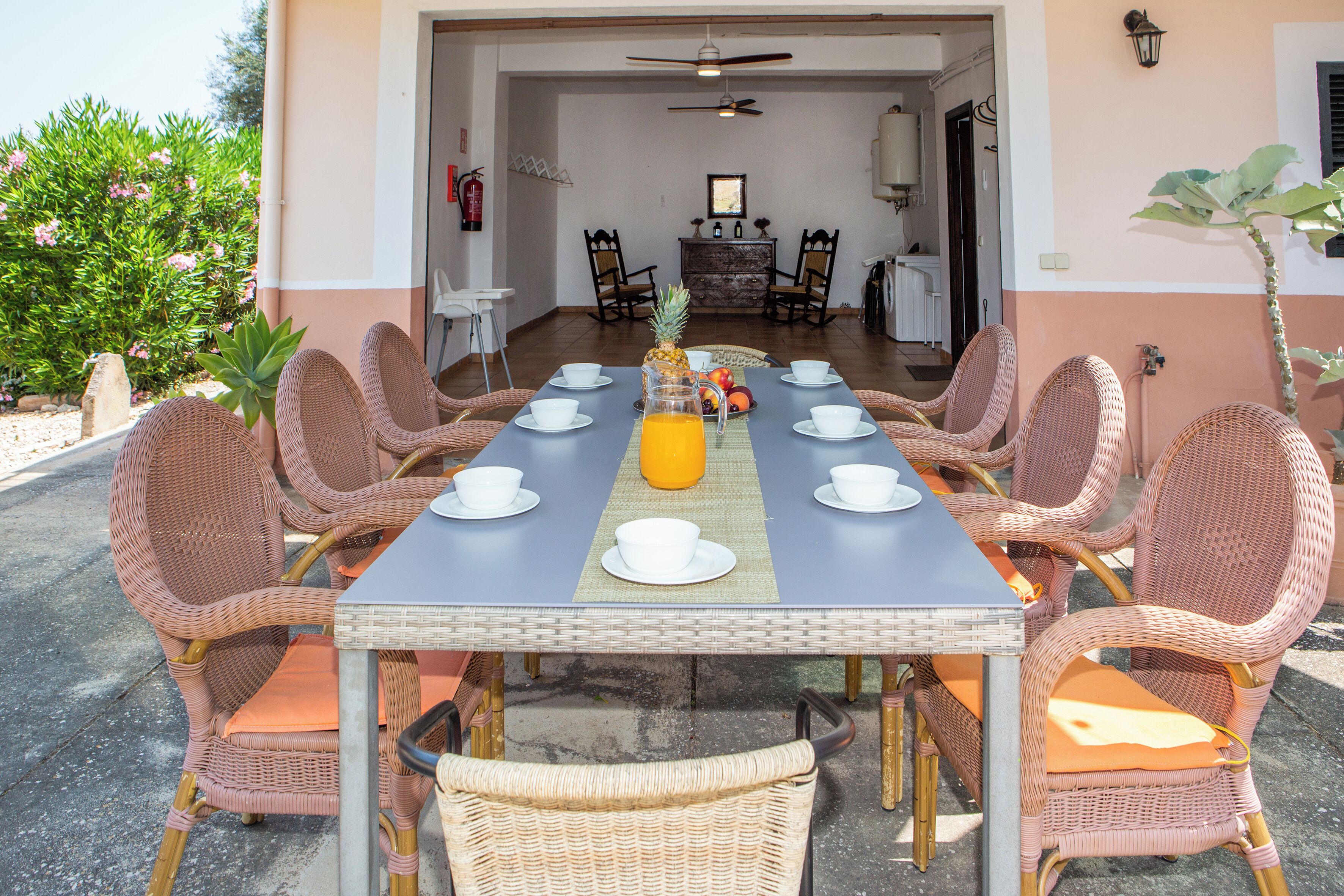 An outdoor dining area with wicker chairs and a table set for six.