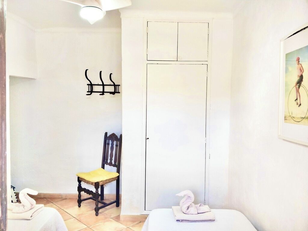 A room with a bed, a chair, a wardrobe, and a wall-mounted towel rack.