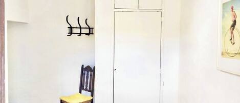 A room with a bed, a chair, a wardrobe, and a wall-mounted towel rack.