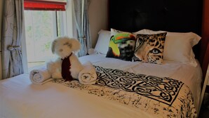 A bed with a rolled towel, patterned bedspread, and two pillows with animal prints.