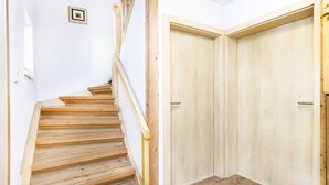 A wooden staircase leading to a room with two wooden doors. - Chalet Struber - Luxury 3 Bedroom Villa In The Centre Of Zell (Zell am See)